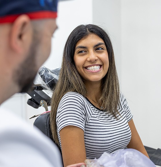 Woman in treatment chair smiling at her oral surgeon