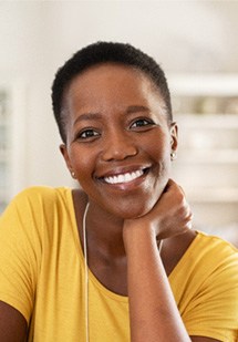 Woman in yellow shirt smiling at home