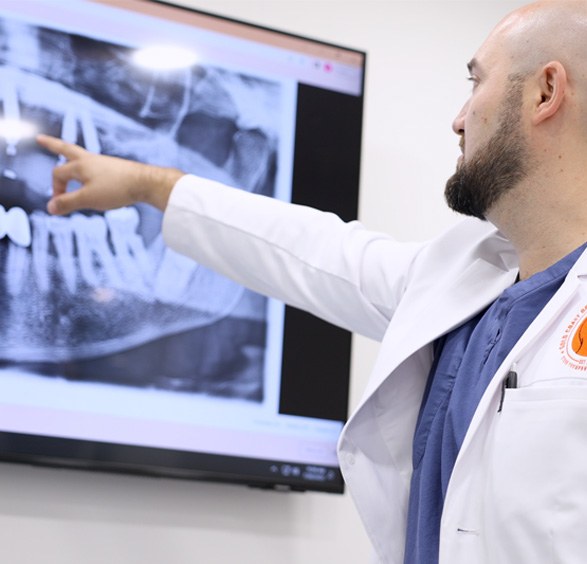 Oral surgeon pointing to x rays of teeth on a screen