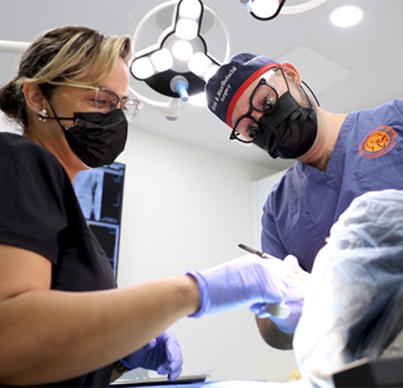 Oral surgeon and assistant treating a patient